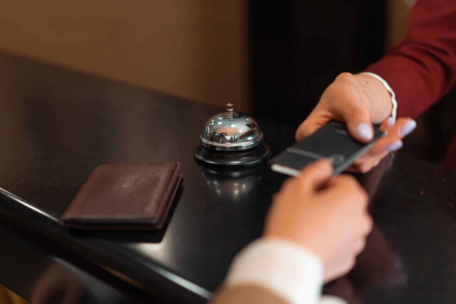 A hotel guest using their phone during a front desk handoff
